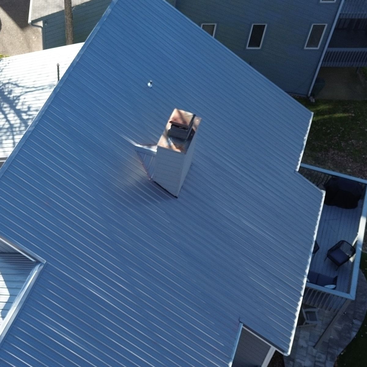 Close view of standing seam metal roof panels and a chimney with matching metal flashing